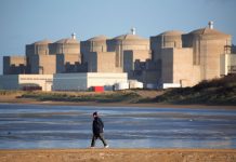 Homme se promenant sur la digue de Petit Fort Philippe devant la centrale nucléaire de Gravelines. Nord de la France. | Northern France: nuclear plant in Gravelines.